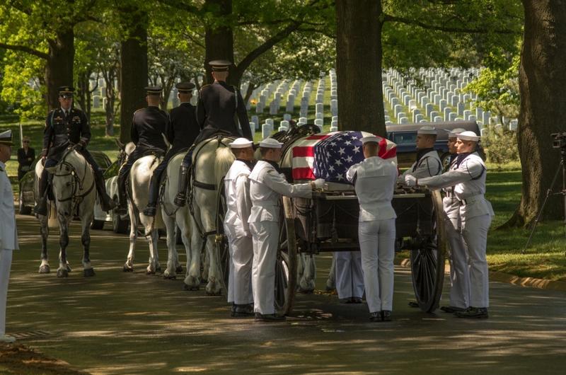 Navy honor guard members stand around a caisson carrying a casket containing the remains of four Vietnam War veterans whose missing remains were accounted for after extensive search and identification efforts that spanned several decades.