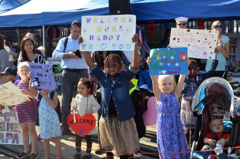 Children and family members of USS Benfold sailors await the crew as the 7th Fleet's newest addition arrives at Yokosuka Naval Base, Japan, Monday, Oct. 19, 2015.