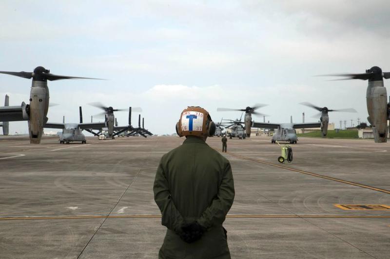 A Marine waits to guide MV-22 Ospreys with Marine Medium Tiltrotor Squadron 265, 31st Marine Expeditionary Unit, during their takeoff from Marine Corps Air Station Futenma, Okinawa.