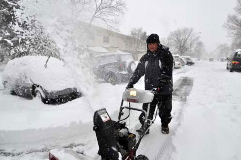 Air Force Master Sgt. Greg Pocaigue uses a snowblower to dig out his car.