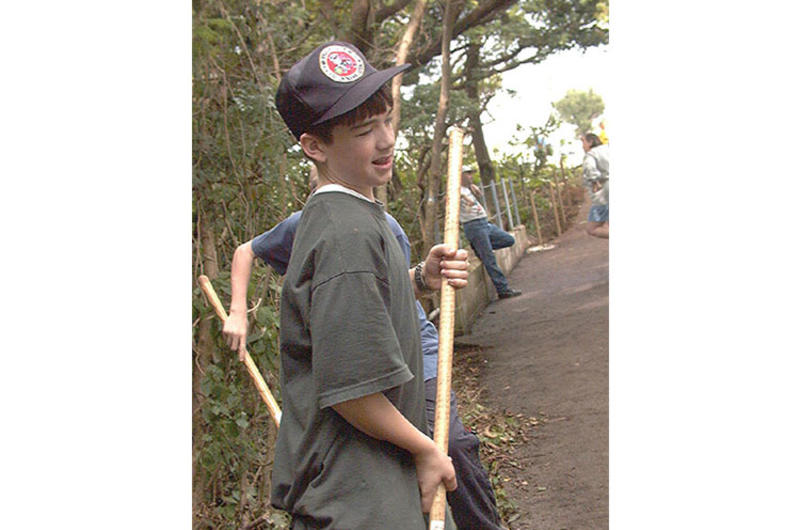 As part of an Eagle Scout project he planned and supervised, Daniel Polaski, 13, helps clear debris from a bridge and shrine site that had been overgrown with vegetation.