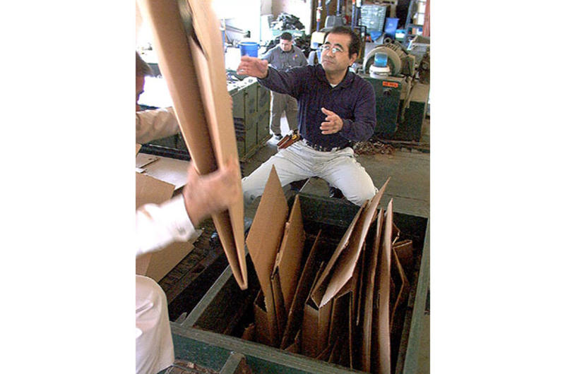 Customer Shinobu Sashida helps load a compactor that scrunches cardboard boxes into 1,100-pound recyclable bales.