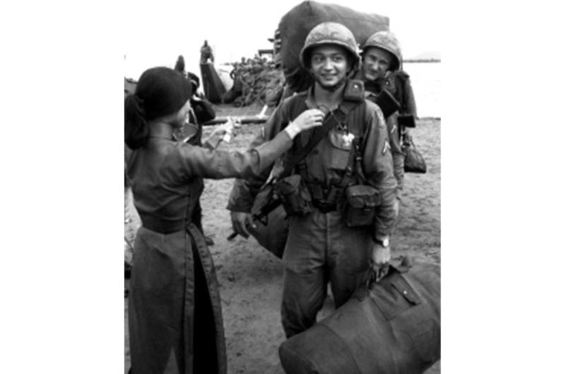 A soldier is given a flower by a Vietnamese girl as the 196th Light Infantry Brigade comes ashore near the end of a long journey from Fort Devens, Mass. in August, 1966.
