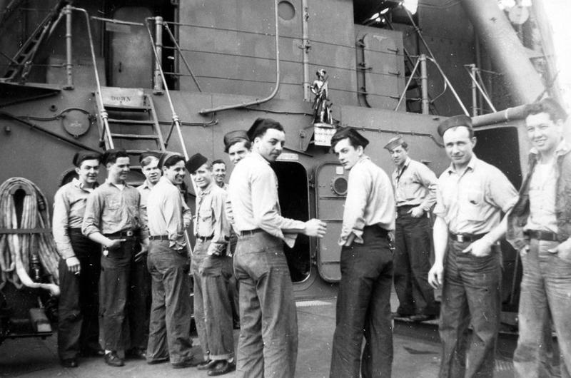 Crewmen of the USS Concord stand on the main deck below a statue of a minuteman mounted on the bulkhead, in this photo taken during the last 15 months of World War II.