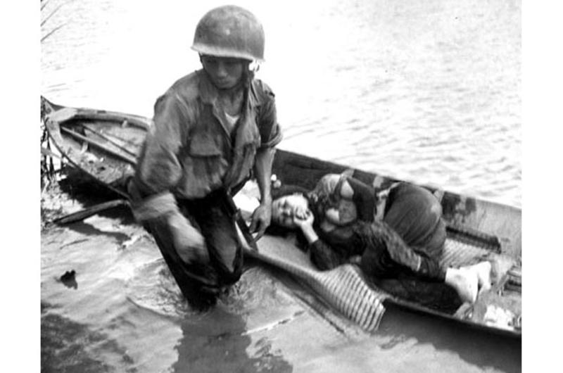 A little girl, hit in the shoulder by a slug from an aircraft machine gun, is tended to by a medic before being evacuated to a hospital by South Vietnamese troops.