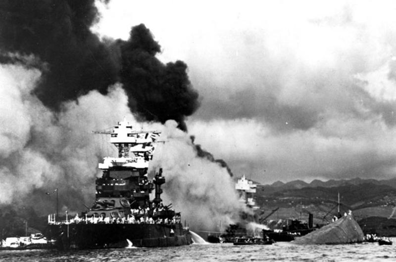 The USS Maryland floats beside the capsized USS Oklahoma, Dec. 7, 1941, as the USS West Virginia burns in the background following Japan's surprise attack on Pearl Harbor, Hawaii.
