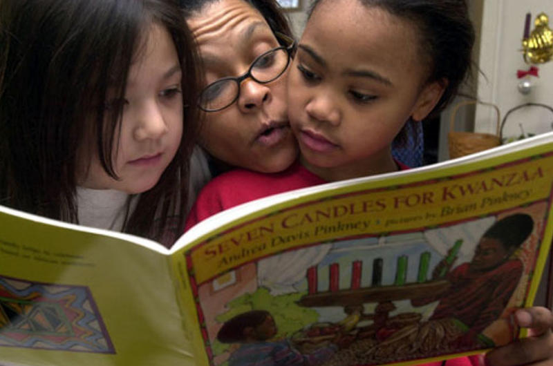 Juana Cephus (center) reads a book about Kwanzaa on Friday with her 8-year-old daughter, Raquel, right, and Raquel's friend, Azlyn Heidt, also 8, at Cephus; home in the Sagamihara Housing Area near Camp Zama, Japan.