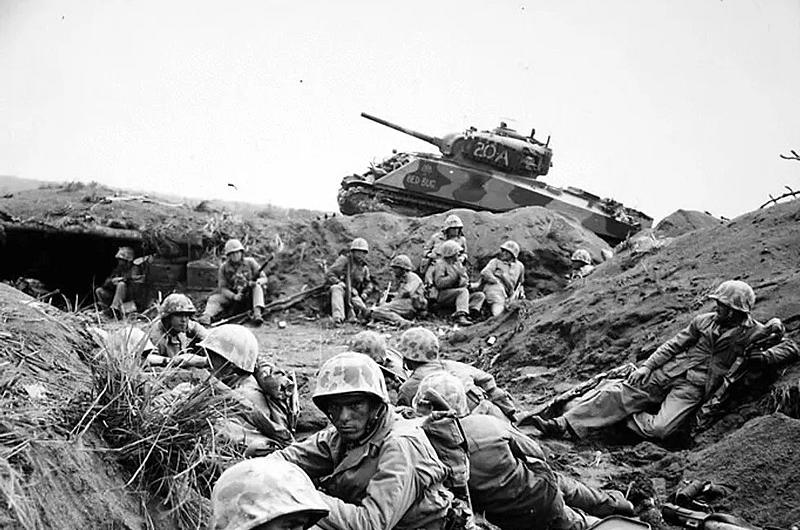 Marines in a ditch with a tank in the background