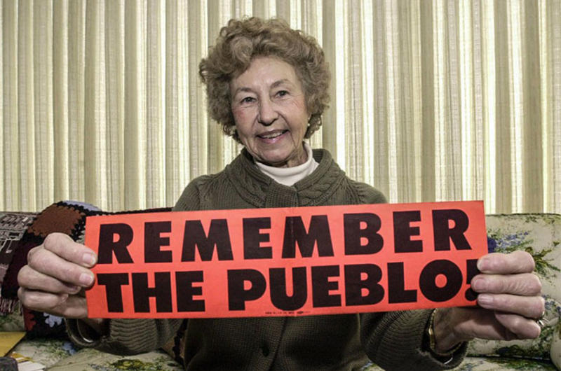 In a February, 2000 photo, Rose Bucher holds up a bumper sticker that she circulated in 1968 in a effort to focus attention on the release of the Pueblo crew.