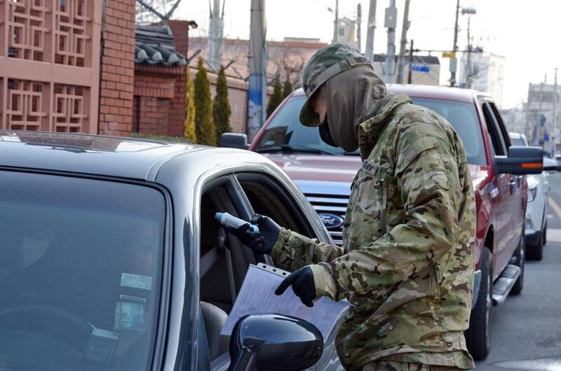 Pvt. Hector Mercado, 23, of the 25th Transportation Battalion, checks temperatures before allowing people to enter Camp Walker in the coronavirus-hit city of Daegu, South Korea, Saturday, Feb. 22, 2020.