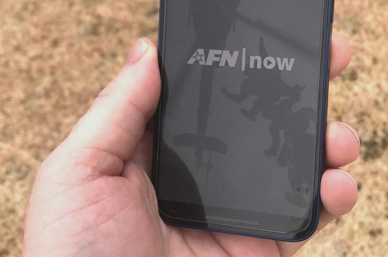 A hand holds a cellphone with the AFN app on it.