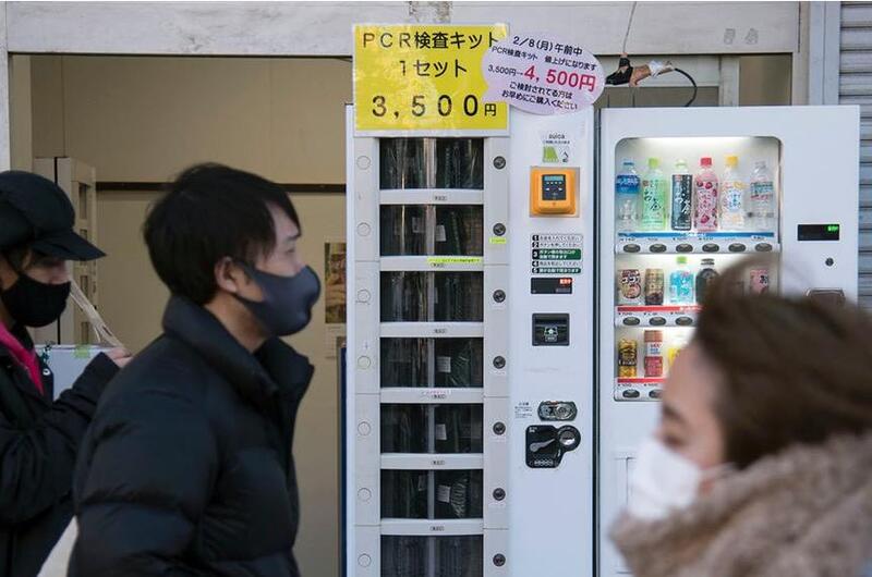 People walk past a vending machine selling polymerase chain reaction kits, which test for the coronavirus, near Ofuna Station in Kanagawa prefecture.