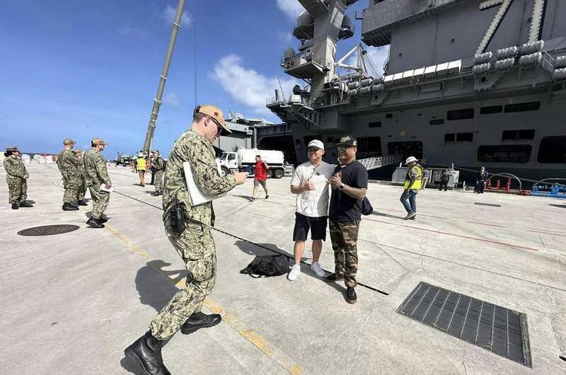 Sailors pose with the USS Theodore Roosevelt after the San Diego-based aircraft carrier arrived at Naval Base Guam, Tuesday, Feb. 6, 2024. 