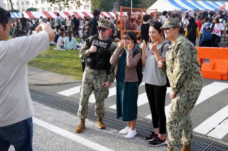 Visitors pose with Navy security during the 44th Friendship Day celebration at Yokosuka Naval Base, Japan, Sunday, Oct. 16, 2022. 