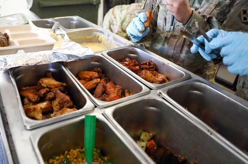 A culinary specialist checks the temperature of chicken wings.