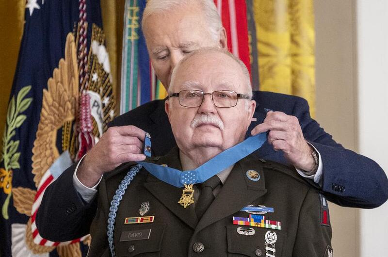 Joe Biden places the Medal of Honor around the neck of an elderly man in military dress uniform.
