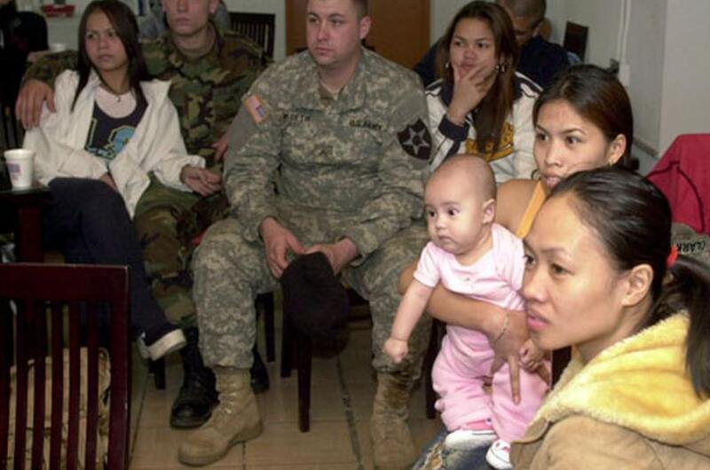 Wives and and a few of their family members listen to speakers at a foreign spouses’ monthly meeting at the Camp Casey United Service Organizations building.