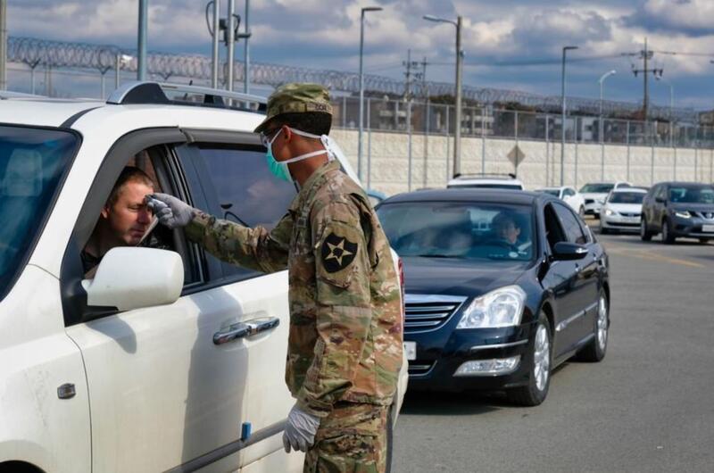 A 2nd Infantry Division soldier checks for a temperature as dozens of vehicles line up to enter the Dongchang-ri gate at Camp Humphreys, South Korea, Wednesday, Feb. 26, 2020.