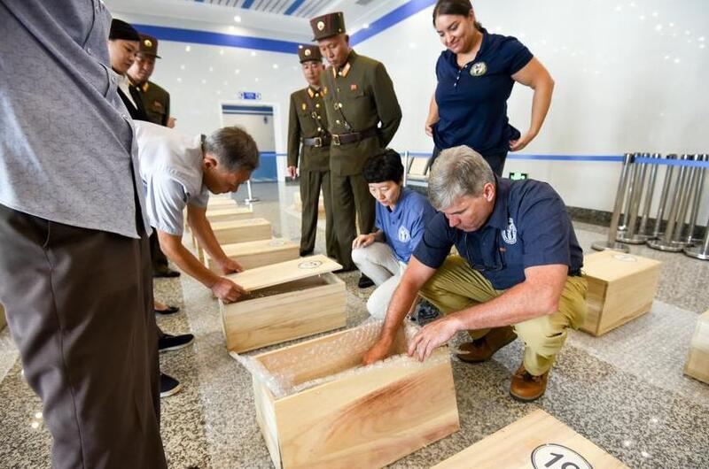 Forensic anthropologists with the Defense POW/MIA Accounting Agency review the contents of cases containing the possible remains of service members lost in the Korean War during a unilateral transfer in Wonsan, North Korea, in July 2018.