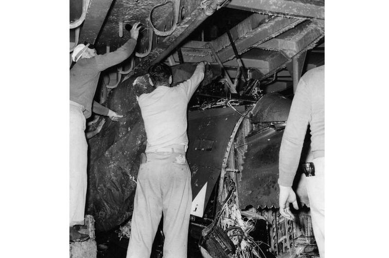 Crew members examine the crushed remains of the Banshee jet