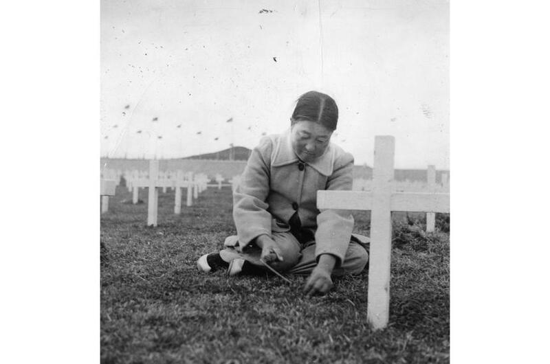 A Korean woman pulls weeds among the gravesites.