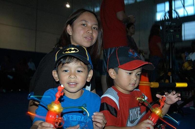 Jermaine Aterrado, 4, (left), and his brother Cedrick, 3, are lost in their glow toys before the  Sesame Street/USO Experience for Military Families show Oct. 6, 2011, at Sasebo Naval Base, Japan. Their mother, Jinky Aterrado, looks on.