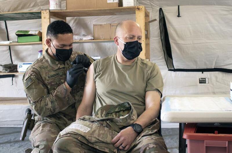 Sgt. Maj. John Shannon receives the COVID-19 vaccine from Sgt. Ryan Kamanu, a medic with the 466th Medical Company Area Support, at the the Role II medical facility at Al Asad Air Base, Iraq, on March 15, 2021.