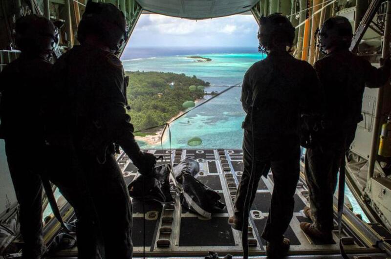 Loadmasters with the 36th Airlift Squadron out of Yokota Air Base, Japan, watch bundles parachute down to Nomwin, Federated States of Micronesia, Dec. 13, 2019, during the annual Operation Christmas Drop.