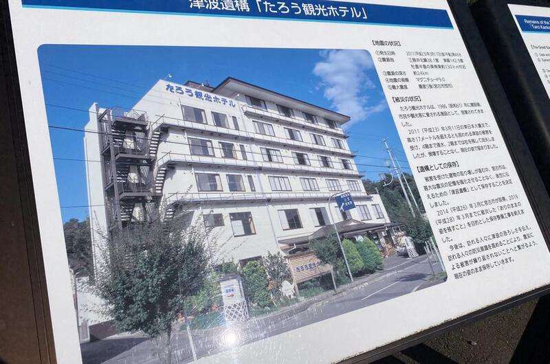 A sign displays Japanese writing and a photo of a multi-story hotel.
