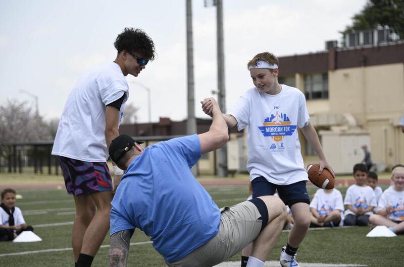 Atlanta Falcons defensive end Morgan Fox is helped to his feet during a youth football camp.