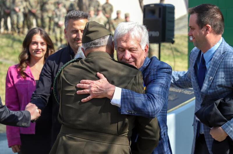 A man with gray hair hugs a general in an Army uniform.