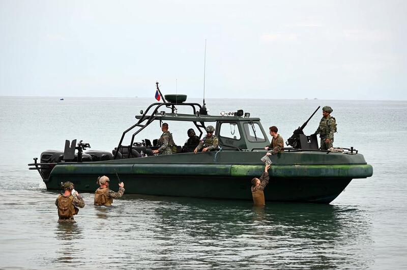 U.S. Marines wade to meet their comrades and Filipino counterparts in a small boat off the coast.
