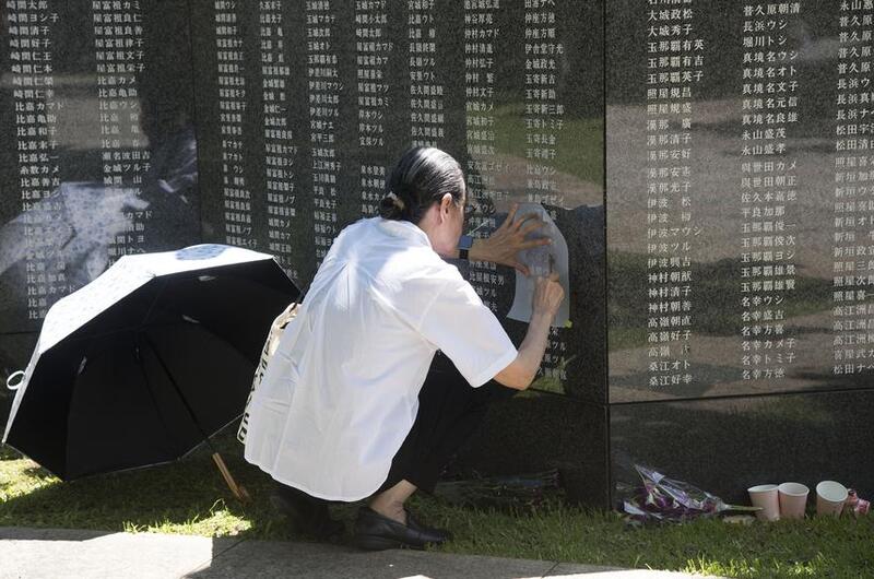 A visitor makes a rubbing of a name on the Cornerstone of Peace monument.