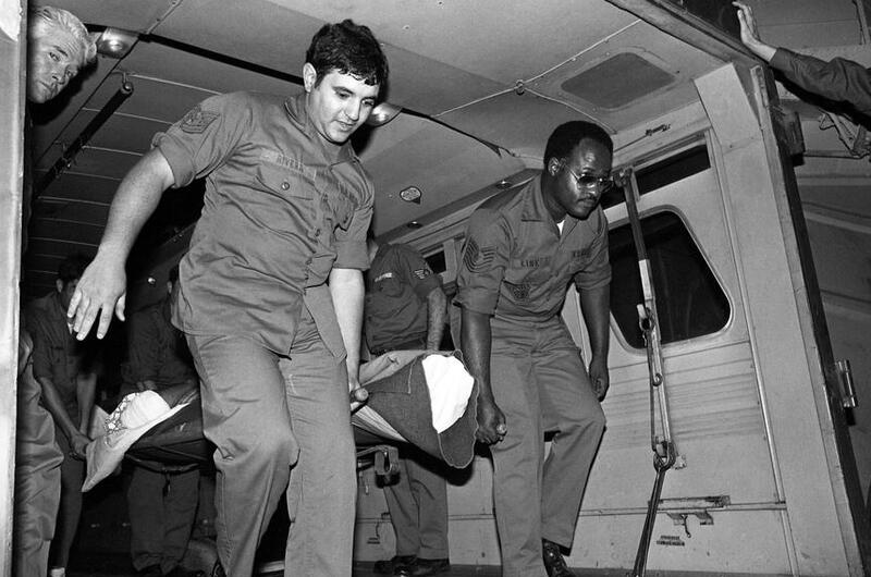 In this black and white photo, men carry a burn victim out of an ambulance.