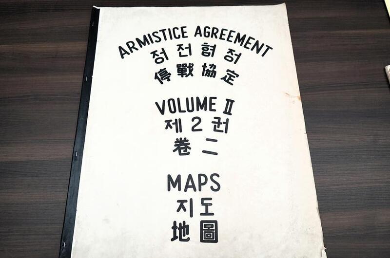 A large booklet that says “Armistice Agreement Maps Volume II” on the cover in black lettering and translated into Chinese and Korean.