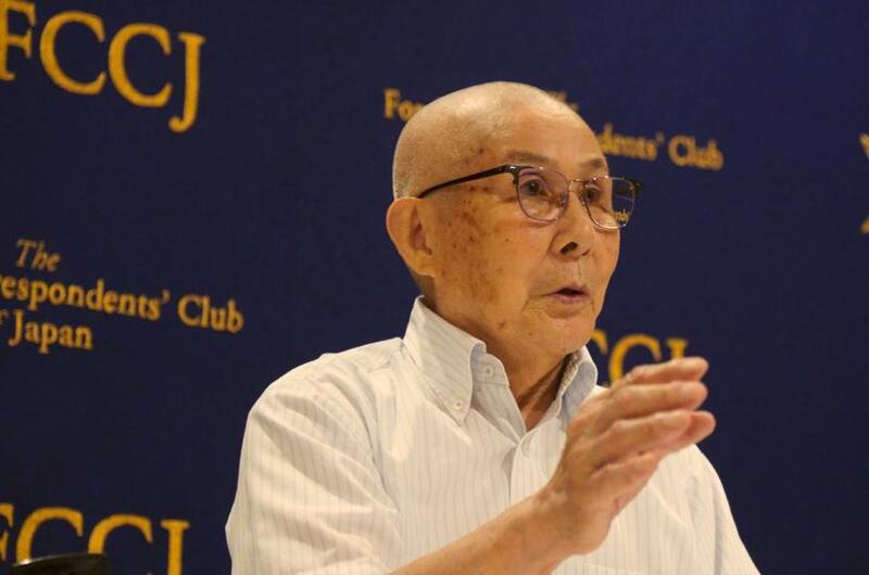 An older man gestures with one hand as he speaks.