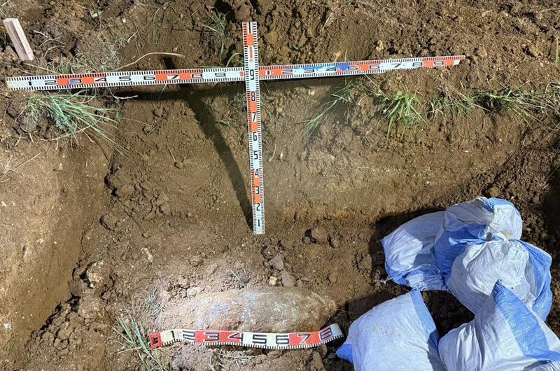 An unexploded bomb is seen being uncovered in the dirt.