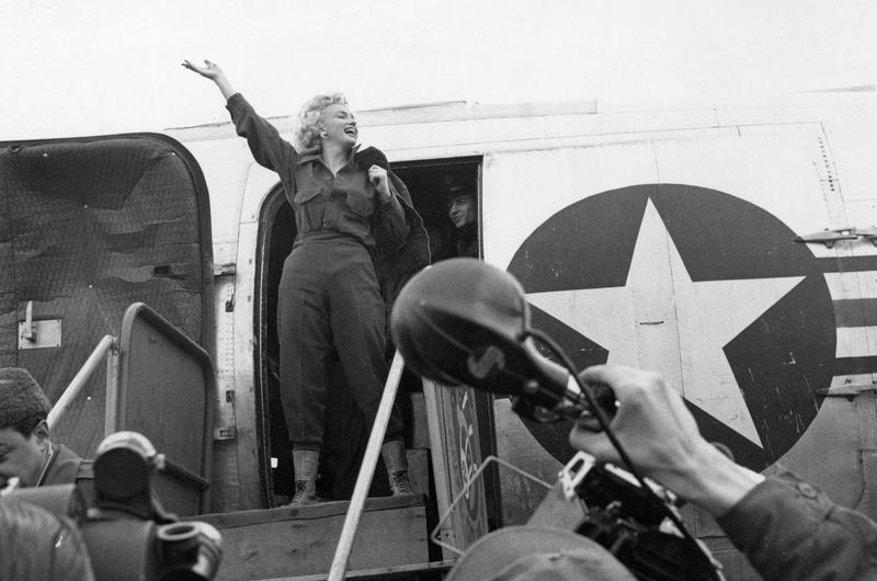 Whoops of joy filled the air as Marilyn Monroe waves an exuberant hello (upper left) as she prepares to debark from the plane that carried her to Seoul.
