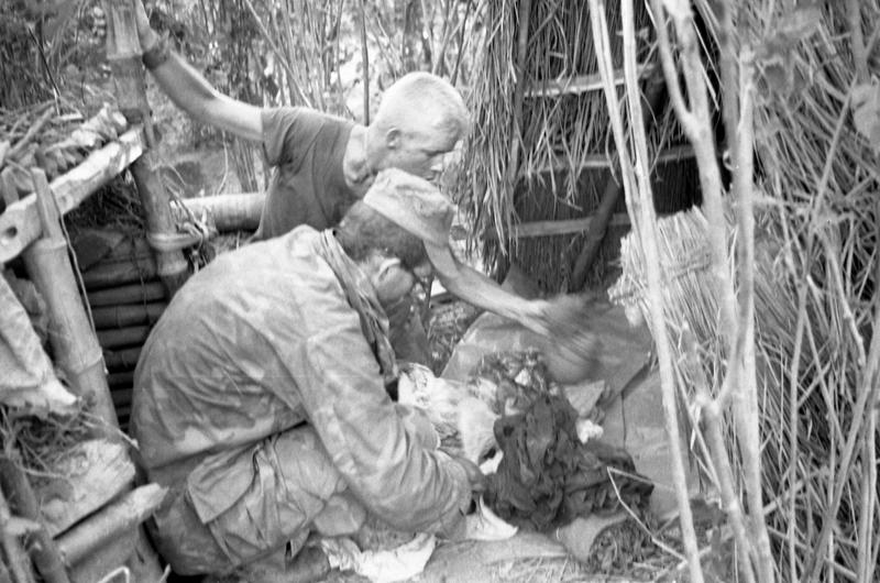 Pfc. Richard C. Black (without hat) and Intelligence Officer Lt. Charles L. Dundas inspect a well concealed enemy hooch and bunker.