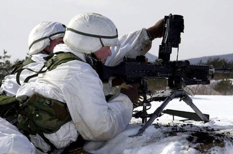 Two soldiers handle a gun on snowy ground.