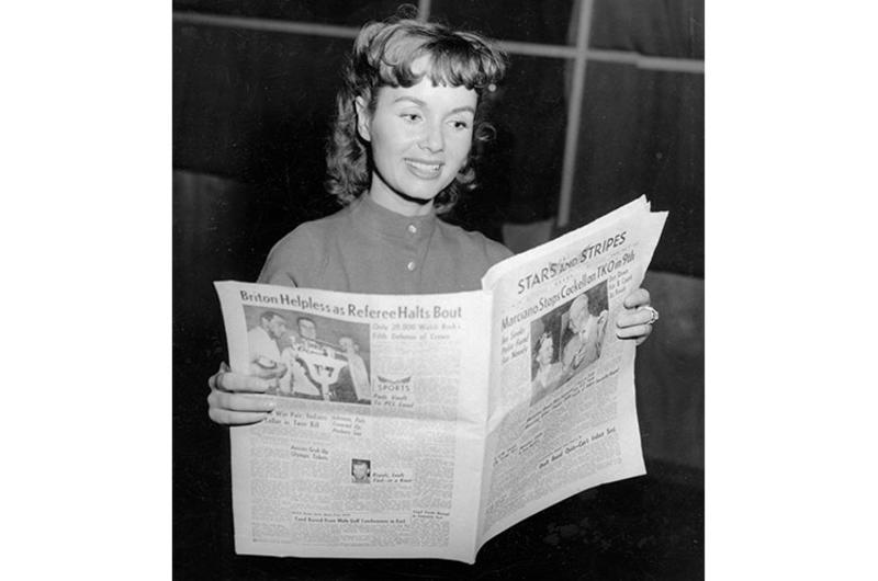 Actress Debbie Reynolds flips through the Stars and Stripes newspaper.