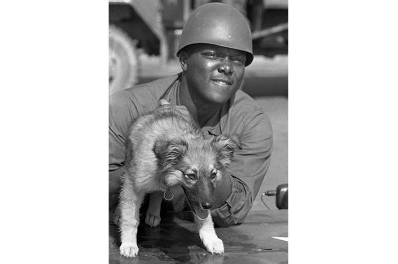 Sp4 Granson Smith of Chicago - just arrived in country with the 6th Battalion, 31st Infantry, 9th Infantry Division troops - plays with a dog as he waits for his unit to move out of the airport onto their next destination.