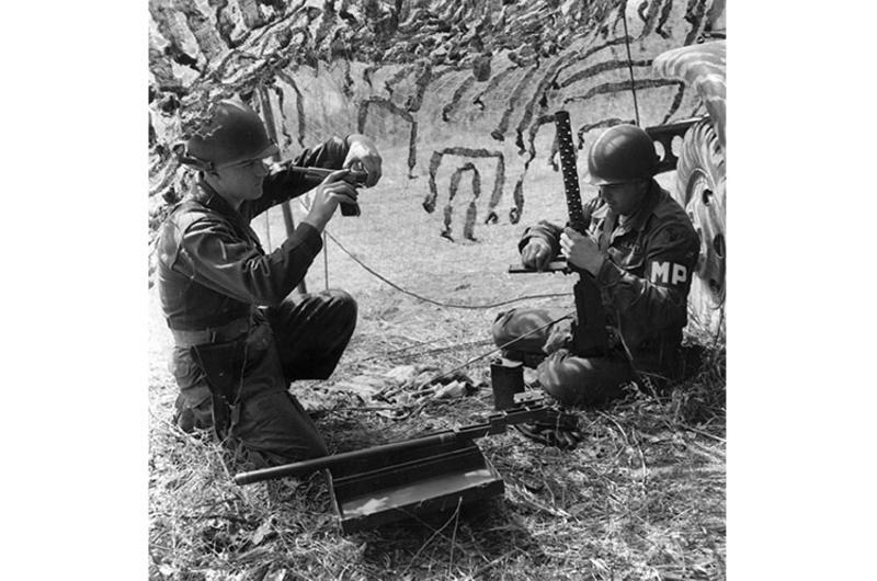 PFC Alfred W. Wood, left, and PFC Elis A. Tatum clean their weapons while waiting for their field assignments.