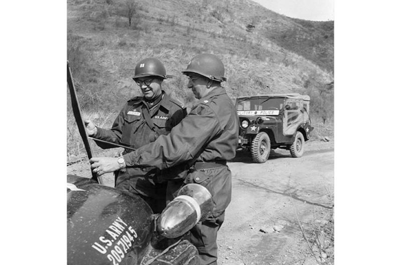Capt. Walter S. DeVeaux, CO of 7th MP CO., gets traffic routing orders from Lt. Col. W.R. Howard.