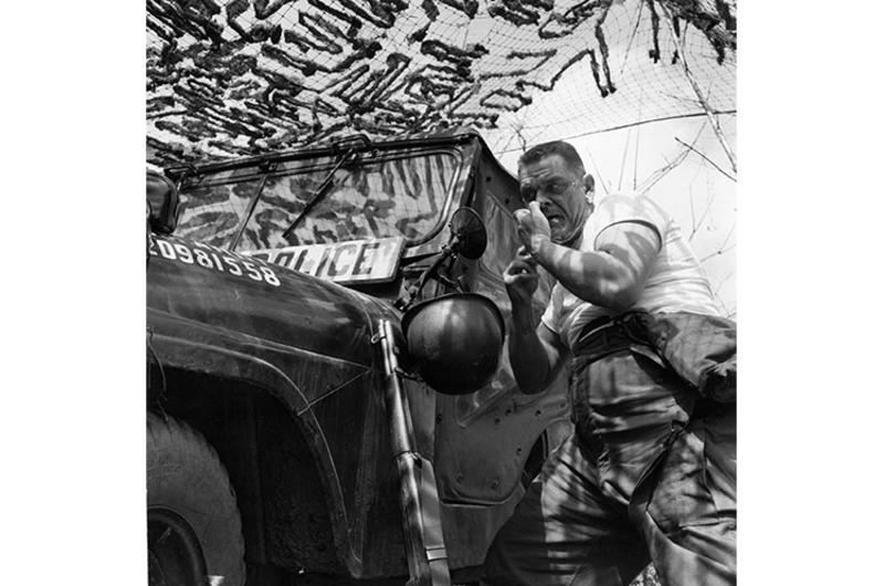 Using Jeep mirror, SP3 Harry W. Wise shaves after a night of guard duty.
