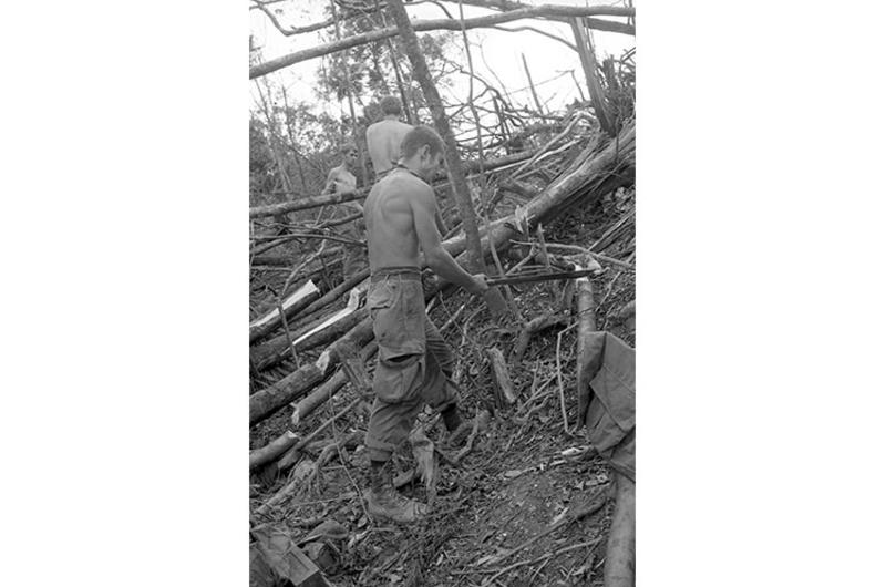 Engineers chopping logs to make a trail to landing zone.