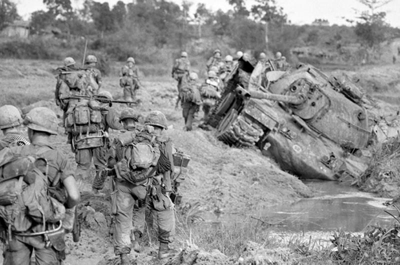 Cavalrymen walk past tank destroyed by NVA earlier this month.