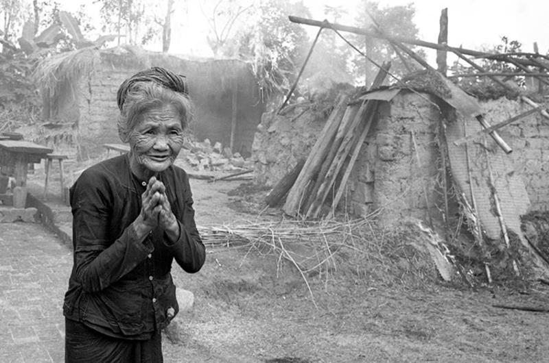 Vietnamese peasant woman watches home burn.