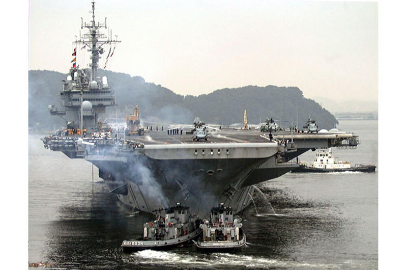 U.S. and Japanese tugs help push the USS Kitty Hawk away from the pier as it leaves for sea trials and exercises in the Philippine Sea.