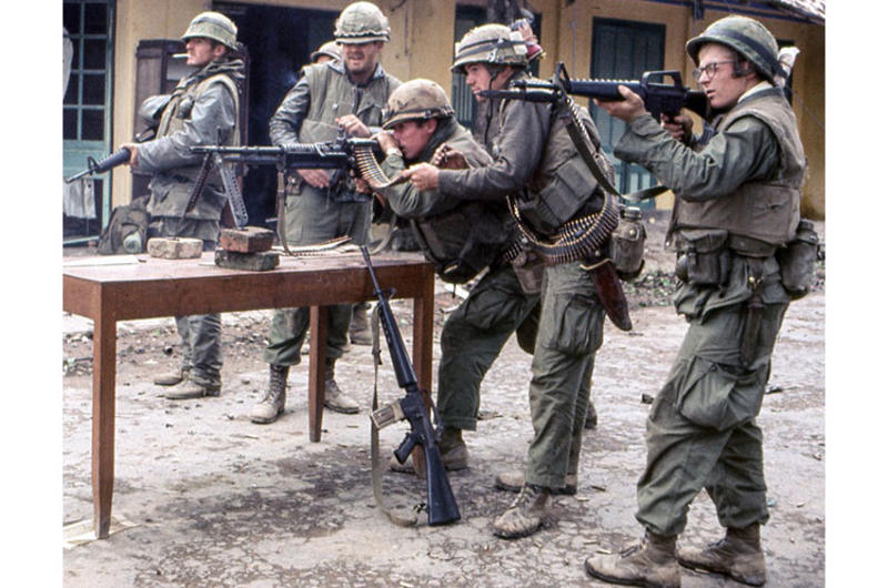 Their machine gun mounted on a kitchen table, U.S. Marines take position on a battle-scarred Hue street amid the bloody effort to retake the city during the Tet offensive.